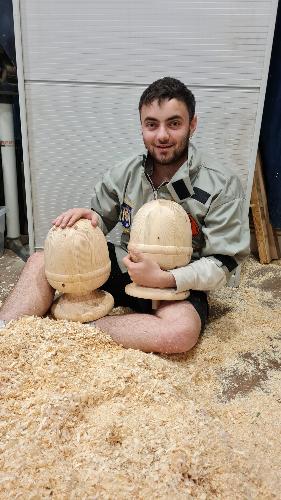 joe sitting on floor covered in sawdust with two unfinished urns